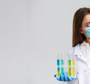 Covid-19, preventing virus, healthcare workers and quarantine concept. Doctor or nurse in clinic lab wear medical mask and gloves, looking at test-tube with coronavirus test vaccine, researching.