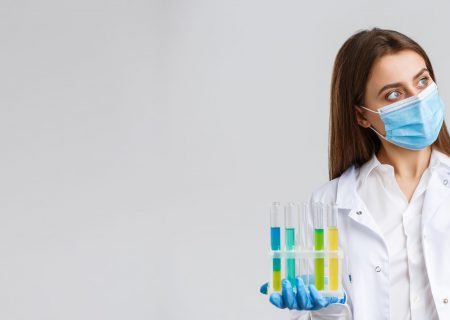 Covid-19, preventing virus, healthcare workers and quarantine concept. Doctor or nurse in clinic lab wear medical mask and gloves, looking at test-tube with coronavirus test vaccine, researching.